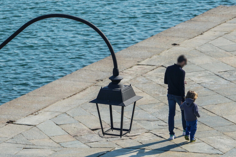 Una padre a passeggio con il proprio figlio - RIPRODUZIONE RISERVATA